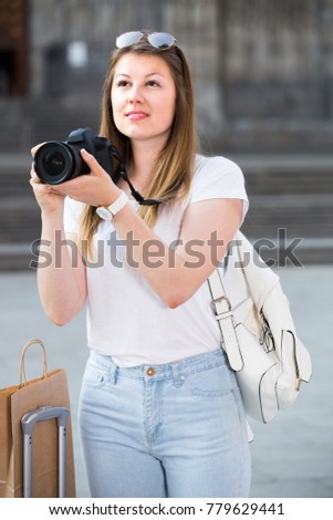 Woman is taking photos on her camera while journey through the city. 