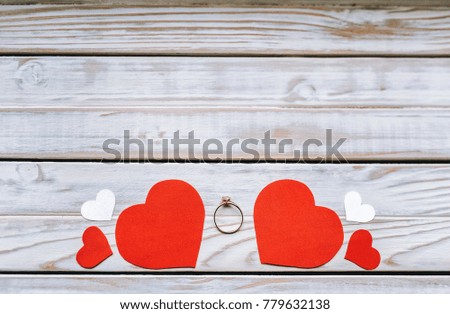 Hearts made of paper and engagement ring on a wooden background. A gift for St. Valentine's Day. marriage proposal. Copy space.