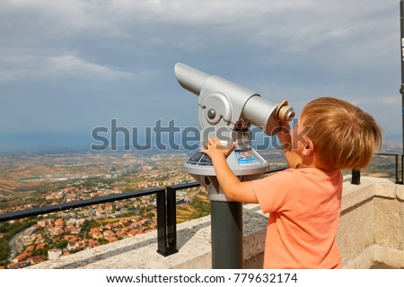 little boy looking through sightseeing binoculars on San Marino