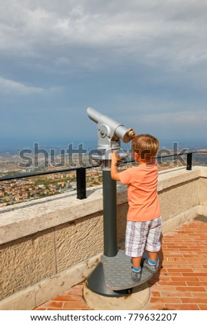 little boy looking through sightseeing binoculars on San Marino