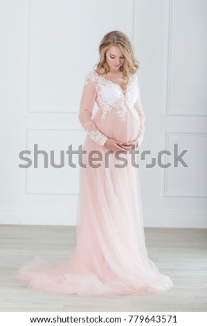 pregnant blonde girl in a pink negligee