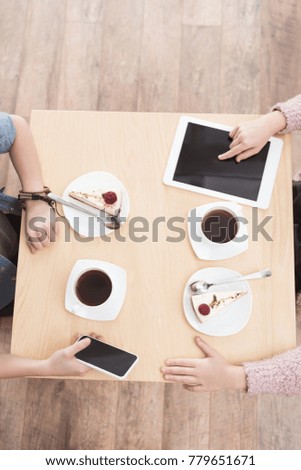 cropped image of kids sitting at table with gadgets on surface at cafe 