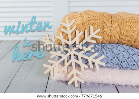 Stack of white cozy knitted sweaters on a wooden table