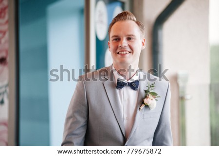 Wedding ceremony. Portrait of the groom. The output of the groom. Gray suit. Blue bow tie.