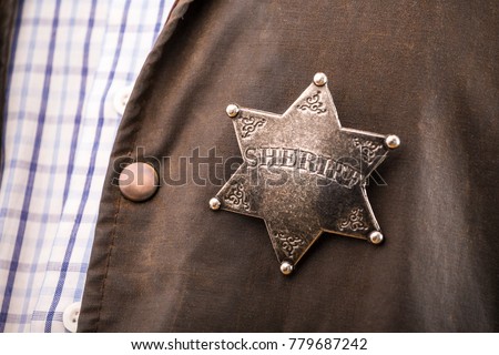 Close up of sheriff badge when on his coat duster Royalty-Free Stock Photo #779687242