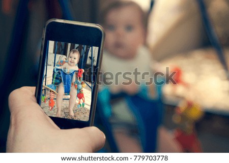dad takes pictures of his child on a mobile phone