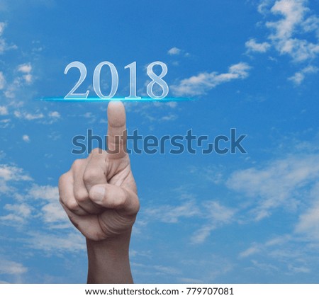 Hand pressing 2018 text over blue sky with white clouds, Happy new year concept