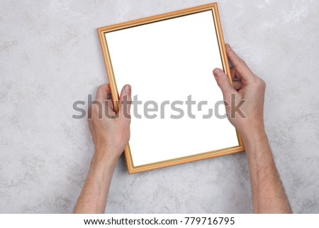 The old man tries to hang a wooden frame with a photograph on the wall. Concept studio shot. Picture isolated on white with patch. 