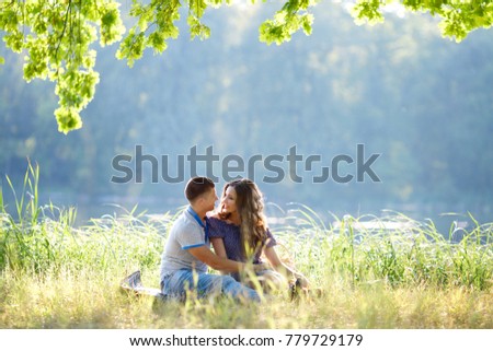 Romance and love. Dating and park. Loving couple sitting together on grass near the lake
