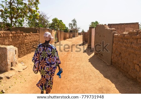 A woman walking in a street of a slum in the suburb of Ouagadougou (Burkina Faso) Royalty-Free Stock Photo #779731948