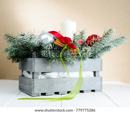 Merry Christmas and Happy New Year! Composition with gray box with fir tree branches, candles and Christmas toys on light background