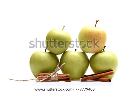 Apples and cinnamon isolated on white background. Composition of fruits and spices, close up. Perfect food mix concept. Pyramid of green apples placed by tied cinnamon sticks.