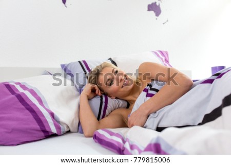 Young blonde woman awakes in her bed in the morning