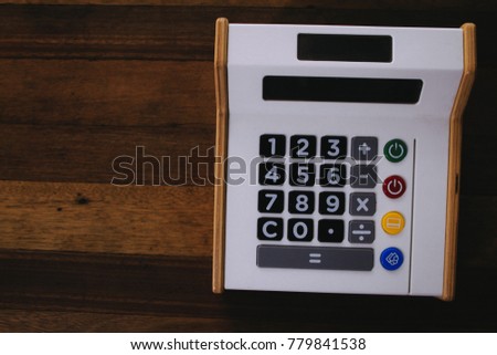 Plastic and wooden toy calculator on wooden desk texture. Concept for fun learning, mathematical thinking, business, accounting, finance.