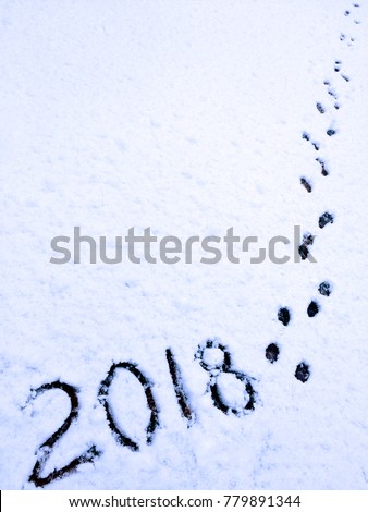 2018 text written by hand on the surface of freshly fallen snow and traces of dog paws, as a symbol of the coming year Dogs on the eastern horoscope