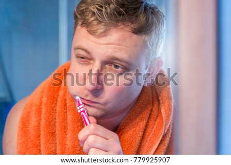 Tired man brushing his teeth