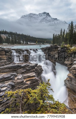 The mountains appear from behind the cloud above Athabasca Falls in Banff National Park.