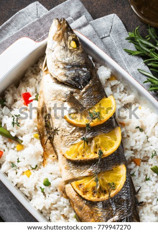 Fish seabass baked with rice and vegetables. Top view with copy space.