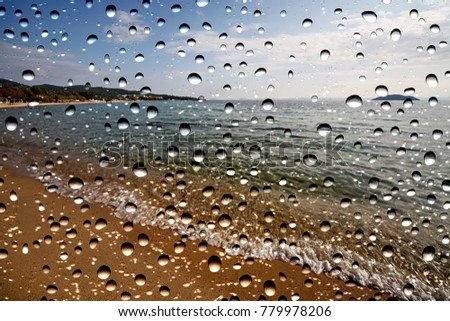 seascape through the window glass covered by raindrops