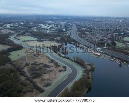 aerial drone view of river surrounded by grass and houses