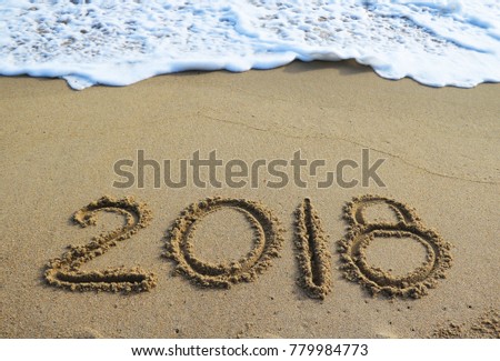 New Year 2018 is coming concept - inscription 2017 and 2018 on a beach sand, the wave is starting to cover the digits 2017 Royalty-Free Stock Photo #779984773