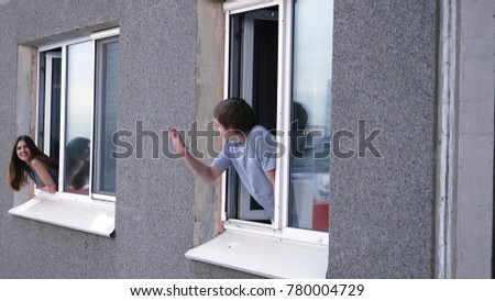 Young man talks with a neighbor through the window. Young man smokes a cigarette and talks with a neighbor from his window Royalty-Free Stock Photo #780004729
