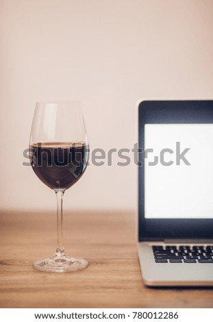 Wine glass with red wine and laptop computer