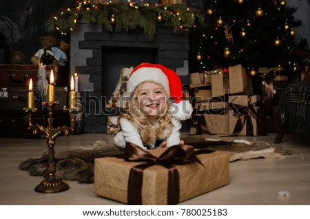 Cute little blonde girl having a gift in her hands on a christmas background. Happy family concept.