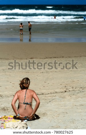 A young girl in bikini sitting on the beach and watching the sea at the Gold Coast of Australia