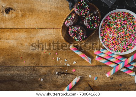 Rainbow wafer stick and donuts on wooden table