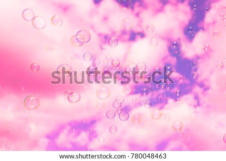 Abstract background : Beautiful soap bubbles reflecting various color floating on sky and white cloud background. Pink digital filter applied.