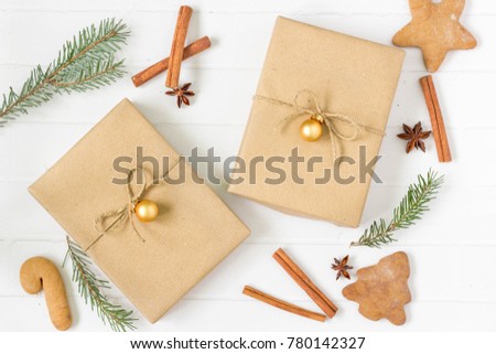 Christmas gift boxes on white, wrapped with natural paper. Christmas decoration in the background, top view.