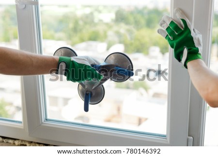Vacuum suction lifter. Hand holding a special tool for carrying a glass pane. Window installation process. Royalty-Free Stock Photo #780146392