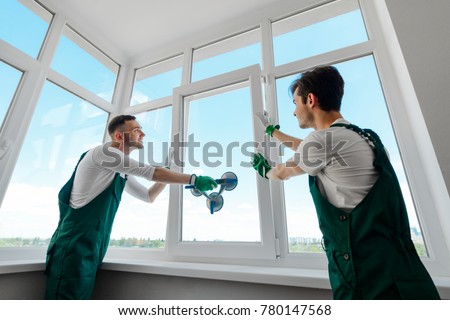 Men are installing a window in the apartment. Almost assembled corner polyvinyl construct by two workers. Royalty-Free Stock Photo #780147568