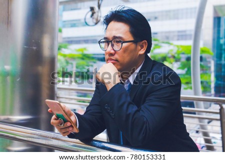 Businessman play smart phone and thinking on walkway. He  is strain after call phone . Photo concept technology for work and Business.