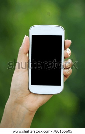 Hand holding cellphone against green background
