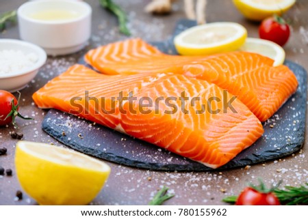 Raw and fresh salmon meat fillet on black stone slate with tomato lemon and other ingredient - Healthy food style