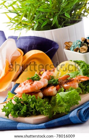 photo of grilled  king prawns on black glass table with reflection