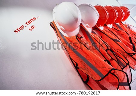 Safety first sign with caption "stop, think...go" made of white and orange helmets and safety vests