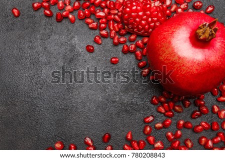 Pomegranate and seeds close-up on dark concrete background