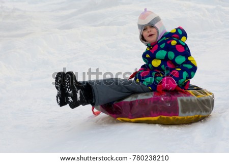 child slides down a snow hill