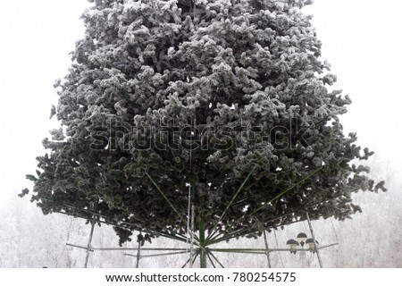 A large artificial Christmas tree is installed on the town square. Winter holiday background
