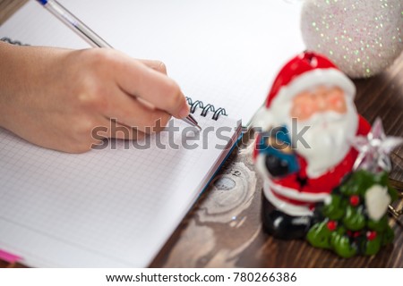 Hands with a pen, notebook and an envelop for letter. A girl is ready to write a letter to Santa Claus. dreams come true, magic holidays and merry Christmas, gifts time