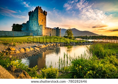 Ancient old Fortress Ross Castle ruin with a lake, green grass and orange clouds in Ireland during golden hour nobody Royalty-Free Stock Photo #780282646