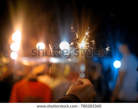 Blurred Sparklers in blur woman hand holding at Market Street City with fire and ice color bokeh.Winter Vivid Color Film grain style.Abstract blur sparklers for celebration christmas party background.