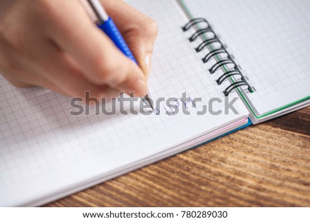 A close photo of a persons writing a letter with a pen.