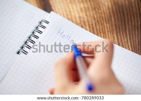 A close photo of a persons writing a letter with a pen.