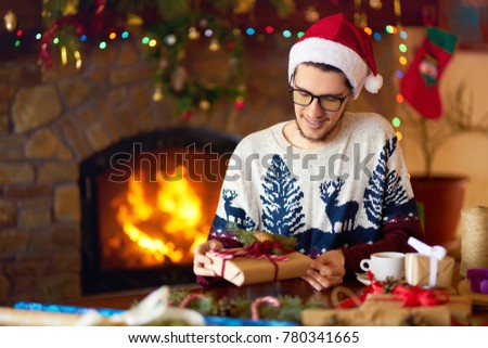 Young boy Tying Ribbon on Christmas Present. New Year's mood, blurred lights. hearth fire in the background
