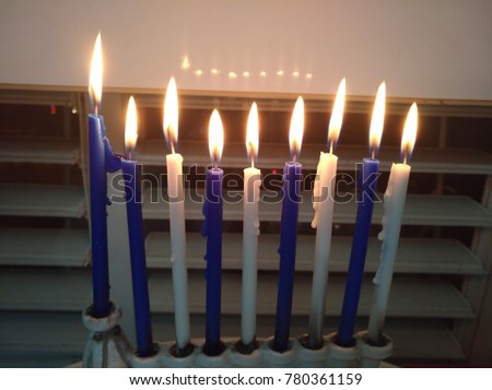 Candles are lit in blue and white on a table and a donut