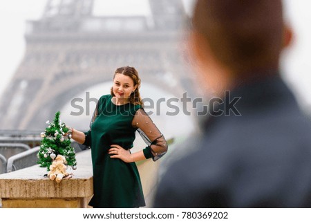 Girl looks at her man and smiles. Eiffel tower background. Christmas tree. Celebrating christmas and New Year in Paris
